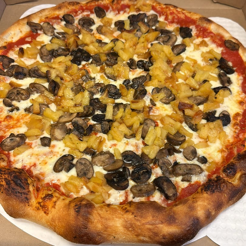 Biaggio Pizzeria's whole pizza with mushrooms and pineapple, in a white pizza box.