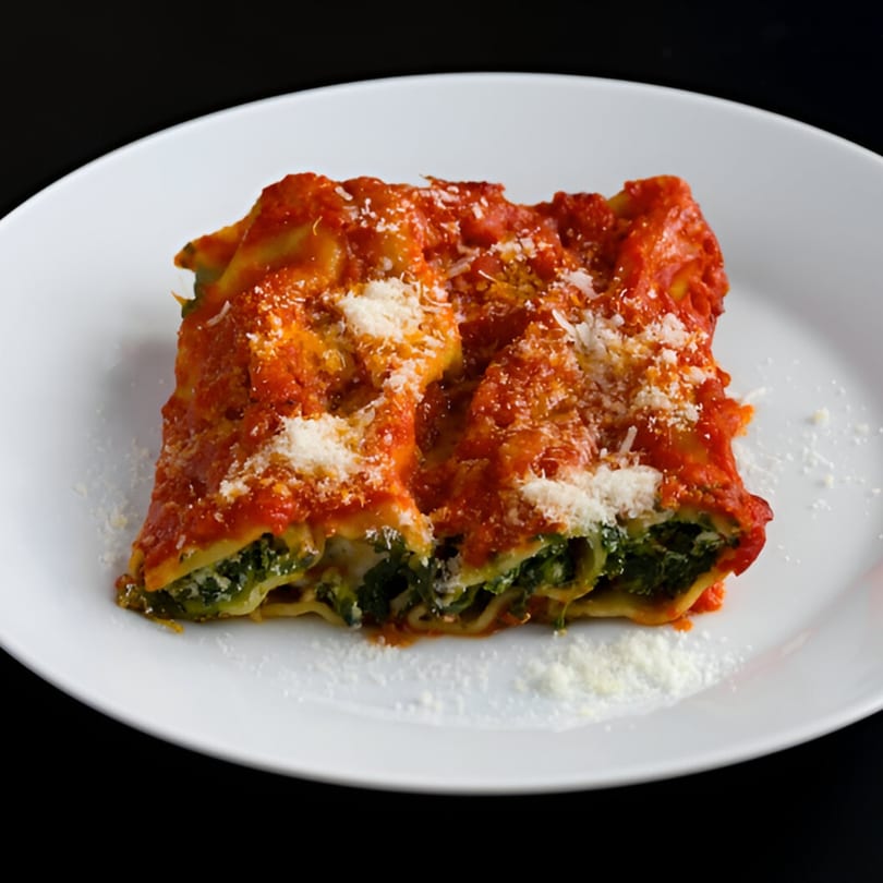 A serving of Biaggio Pizzeria's cannelloni, topped with red sauce and grated parmesan cheese.
