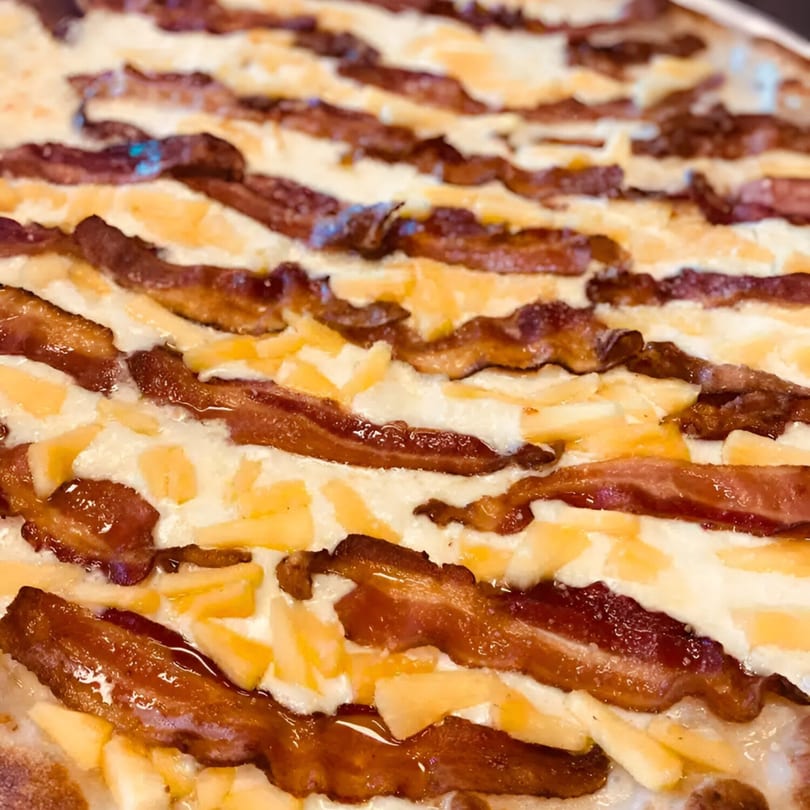 Close-up of a Biaggio Pizzeria & Family Restaurant pizza with crispy bacon strips and melted cheese.